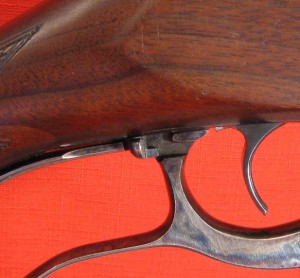 Sliding safety located at top of lever behind trigger